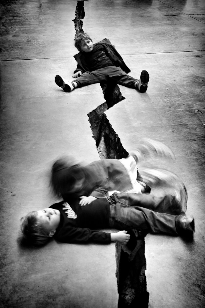Children lying and playing on paving, seen from above.